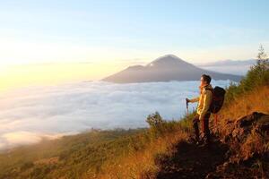 Peak Paradise, Asian Model on Mount Batur Summit with Ocean of Clouds under Azure Sky photo