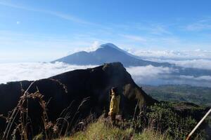 Peak Paradise, Asian Model on Mount Batur Summit with Ocean of Clouds under Azure Sky photo
