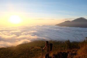 Peak Paradise, Asian Model on Mount Batur Summit with Ocean of Clouds under Azure Sky photo