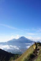 Asian Adventure, Man Model on Mountain Summit, Carrying Hiking Gear under Blue Sky above Ocean of Clouds photo