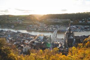Tourist famous destination town of Dinant in Wallonia region in sunset. The town is spread around the river La Meuse with a huge rock in the middle with fortifications photo