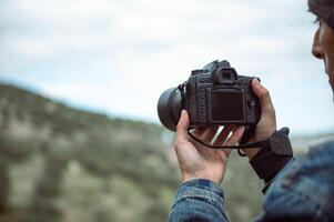 Details on the digital camera in the hands of male photographer capturing the beauty of nature, photographing mountains photo