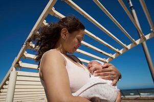 Woman carrying her newborn baby while walking together on the city on warm sunny day photo