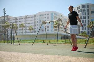 Young athletic man exercising with a jumping skipping rope in urban environment. photo