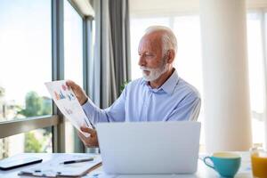 Focused senior business man presenting charts and graphs on video call online. Mature business man having conference call with client on laptop explaining how business work photo