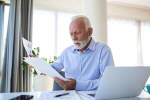 Focused senior business man presenting charts and graphs on video call online. Mature business man having conference call with client on laptop explaining how business work photo