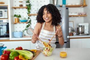 Young Woman Cooking in the kitchen. Healthy Food - Vegetable Salad. Diet. Dieting Concept. Healthy Lifestyle. Cooking At Home. Prepare Food photo