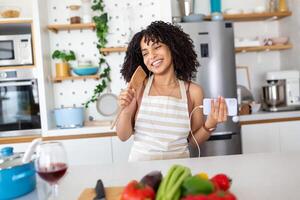 adorable alegre hermosa mujer cantando, bailando con cuchara y pan cubrir en moderno ligero blanco cocina, Cocinando hecho en casa desayuno plato con Doméstico productos foto