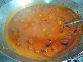 someone puts raw meat into a hot pan to cook rendang or beef curry with Indonesian spices photo