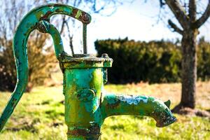 antiguo mano agua bomba en un bien en el jardín, riego y ahorro agua, rural medio ambiente foto