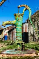 Old hand water pump on a well in the garden, watering and saving water, rural environnement photo