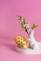 White rabbit, blossom twig and Easter eggs on a pink background photo