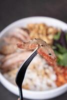 Meat on fork close-up on background of bowl with rice, veal and vegetables. photo