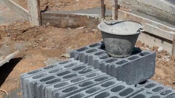 construcción antecedentes. ladrillos y bloques son arreglado en ordenado pila de algo en el suelo. y allí estaba un Cubeta de cemento metido en cima. construcción pared antecedentes. foto