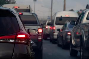 Rear side of dark car with turn on brake light on the road. Traffic jam on the evening. Cars lined up on the road in urgent traffic condition. photo