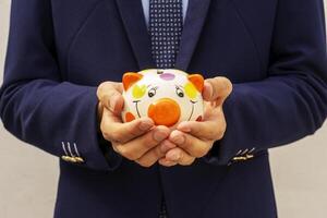 Businessman holding a piggy bank in his hands symbol of savings and good investments photo