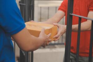 Asian delivery express courier young man use giving boxes to woman customer he wearing protective face mask at front home photo