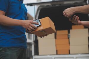 asiático entrega Rápido mensajero joven hombre utilizar dando cajas a mujer cliente él vistiendo protector cara máscara a frente hogar foto