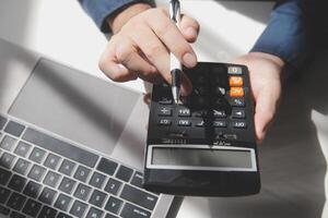 businessman working on desk office with using a calculator to calculate the numbers, finance accounting concept photo
