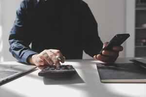 businessman working on desk office with using a calculator to calculate the numbers, finance accounting concept photo