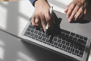 Cropped image of a young man working on his laptop in a coffee shop, rear view of business man hands busy using laptop at office desk, young male student typing on computer sitting at wooden table photo