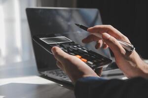 businessman working on desk office with using a calculator to calculate the numbers, finance accounting concept photo
