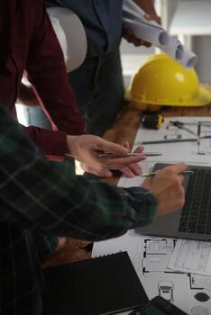 Engineers are consulting the team to design an architectural structure for clients with blueprints and building models to work at office. photo