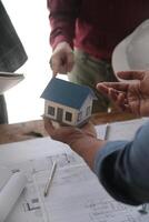 Engineers are consulting the team to design an architectural structure for clients with blueprints and building models to work at office. photo
