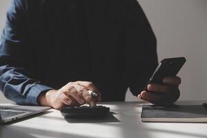 businessman working on desk office with using a calculator to calculate the numbers, finance accounting concept photo