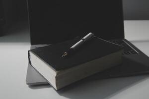 Office workplace with text space, White wooden table with office supplies tablet, desktop computer and book, top view, over light photo