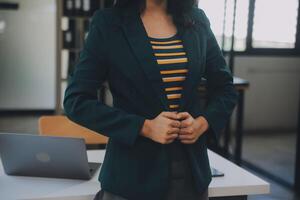 Charming Young asian businesswoman sitting on laptop computer in the office, making report calculating balance Internal Revenue Service checking document. photo