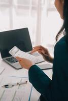 Businessman using a calculator to calculate numbers on a company's financial documents, he is analyzing historical financial data to plan how to grow the company. Financial concept. photo