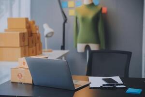 Emprendedora de pequeñas empresas o mujer asiática independiente que usa una computadora portátil con caja, joven mujer asiática de éxito con su mano levantada, caja de embalaje de marketing en línea y entrega, concepto de pyme. foto