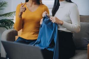 asiático mujer amigos Pareja hablar a cámara a vender el ropa a hogar. joven atractivo negocio personas hembra En Vivo transmisión y demostración ropa a cliente en en línea Al por menor a ventas a oficina Tienda foto