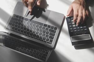 businessman working on desk office with using a calculator to calculate the numbers, finance accounting concept photo