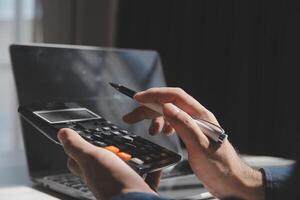 businessman working on desk office with using a calculator to calculate the numbers, finance accounting concept photo