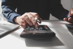 businessman working on desk office with using a calculator to calculate the numbers, finance accounting concept photo