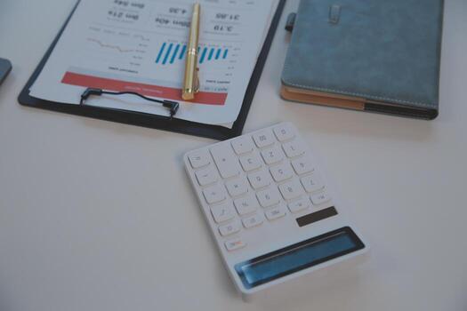 Close up view of simple workspace with laptop, notebooks, coffee cup and tree pot on white table with blurred office room background photo