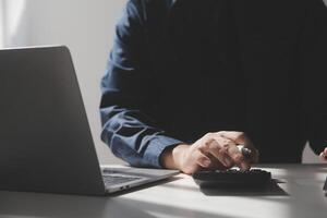 businessman working on desk office with using a calculator to calculate the numbers, finance accounting concept photo