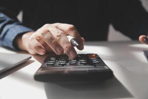 businessman working on desk office with using a calculator to calculate the numbers, finance accounting concept photo
