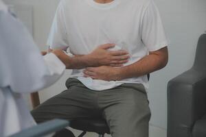 Man suffering with severe stomach pain sitting at home. Hand of mature guy holding abdomen suffering from ache, diarrhea or indigestive problem. Caucasian guy pressing on belly on painful sensation photo