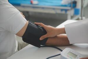 Male doctor uses a blood pressure monitor to check the body pressure and pulse of the patients who come to the hospital for check-ups, Medical treatment and health care concept. photo