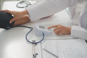 Male doctor uses a blood pressure monitor to check the body pressure and pulse of the patients who come to the hospital for check-ups, Medical treatment and health care concept. photo