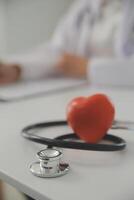 Hands of doctor woman holding red heart, showing symbol of love, human support to patient, promoting medical insurance, early checkup for healthcare, cardiologist help. Close up of object photo