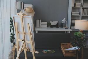 Cropped image of female artist standing in front of an easel and dipping brush into color palette photo