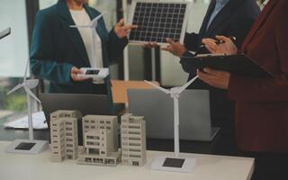 Close-up at tablet, Engineers pointing at tablet with their hands. To jointly design the use of renewable energy with wind and solar energy. Concept of using renewable energy. photo