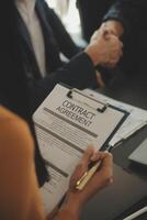 Justice and Law concept. Legal counsel presents to the client a signed contract with gavel and legal law or legal having team meeting at law firm in background photo