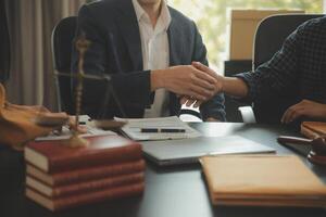 Justice and Law concept. Legal counsel presents to the client a signed contract with gavel and legal law or legal having team meeting at law firm in background photo