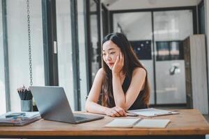 A young freelancer concentrates on her laptop screen, immersed in her work at a wooden desk in a bright home office, a portrait of dedication and modern entrepreneurship. photo