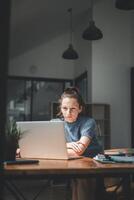 un mujer, profundamente absorto en su trabajar, se inclina adelante hacia su ordenador portátil pantalla, su expresión uno de intenso atención y determinación en un bien iluminado moderno oficina. foto